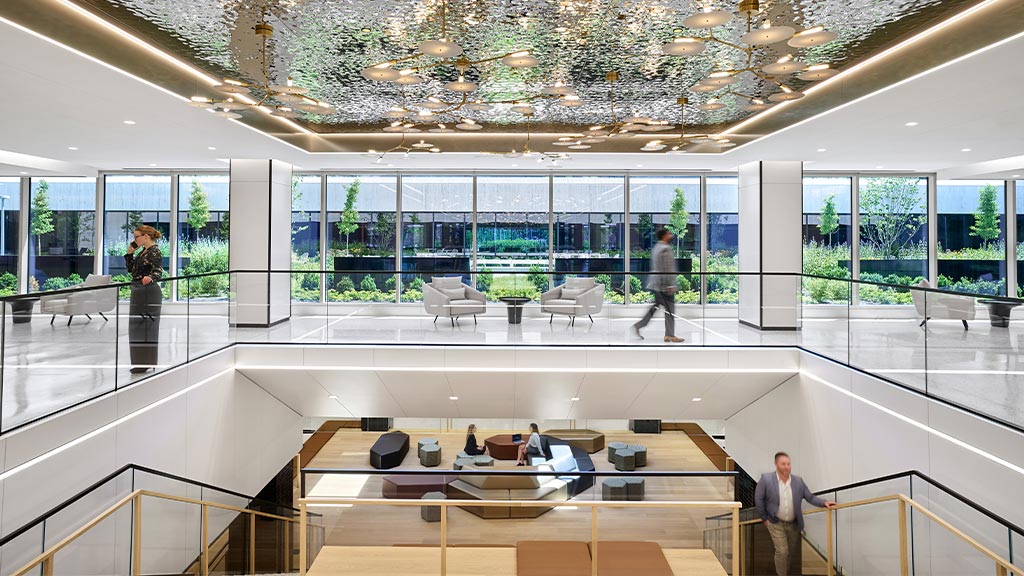A group of people in a large room with glass walls and a large glass ceiling.