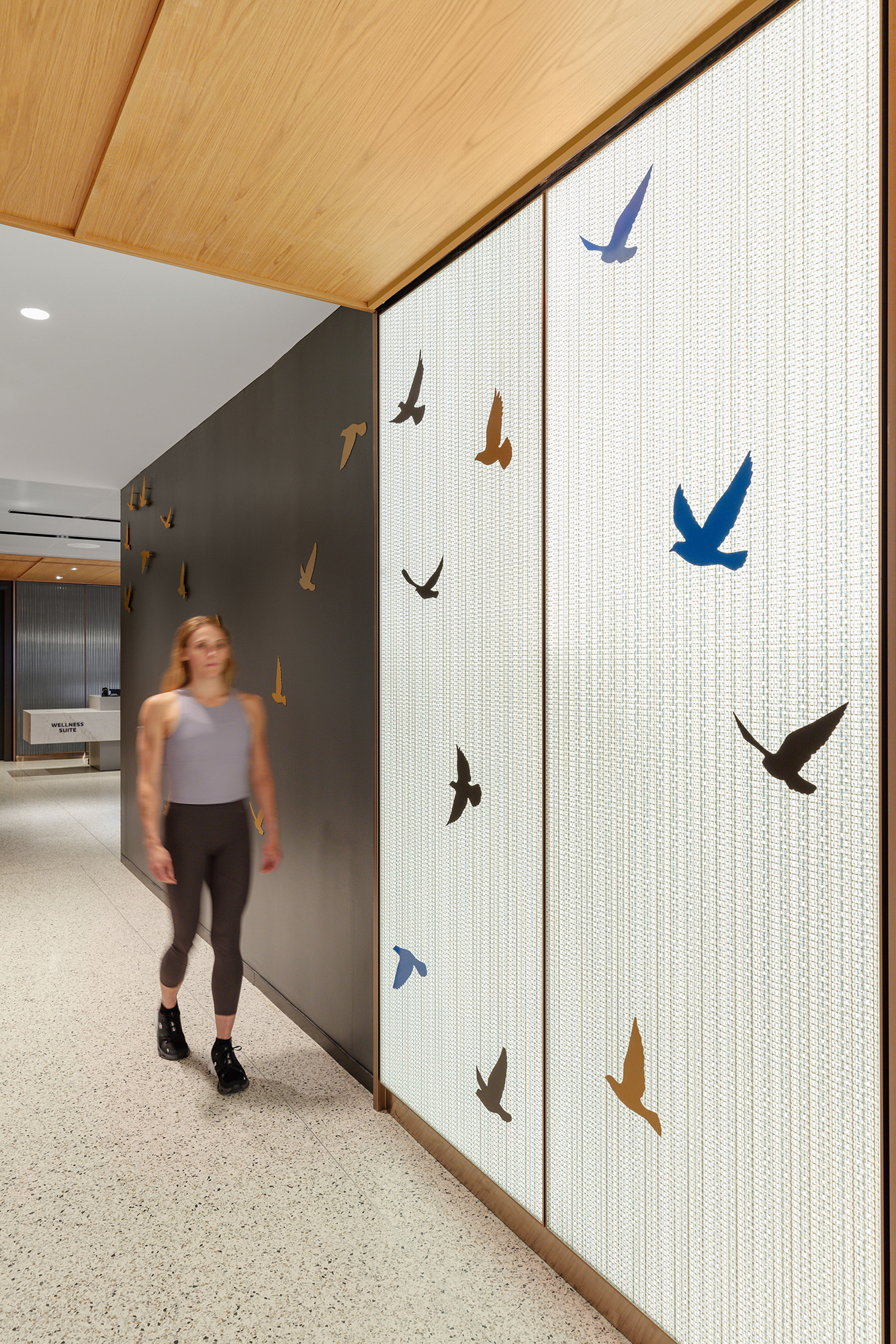 A person standing next to a wall with birds on it.