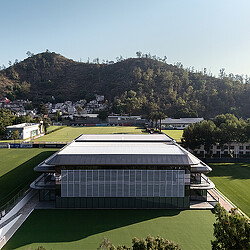 A large building with a hill in the background.