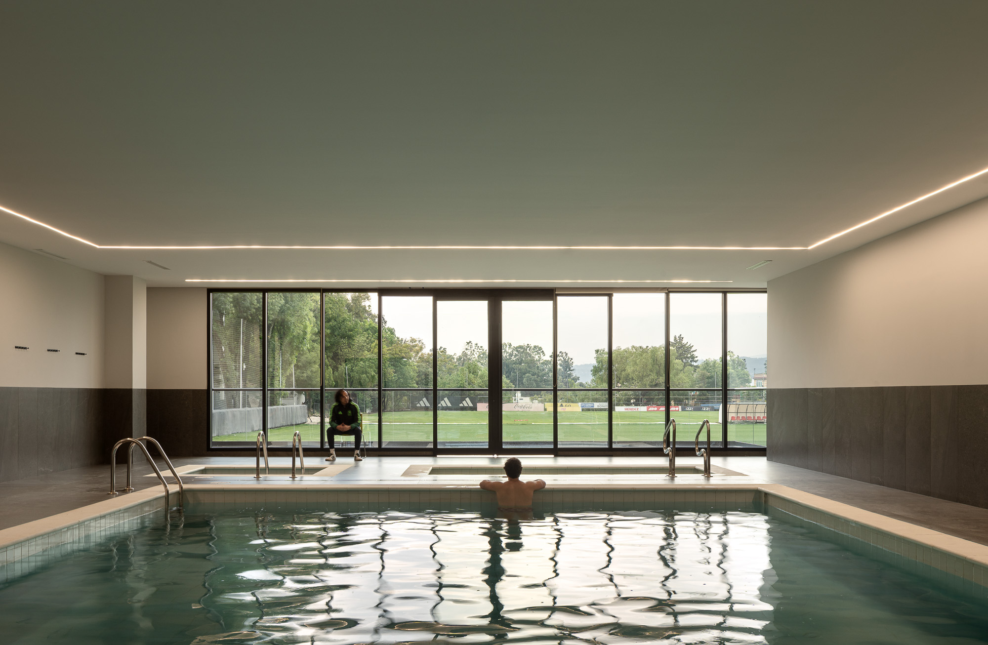 A man and woman sitting in a large indoor pool.