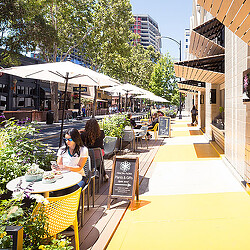 A group of people sitting at tables outside.