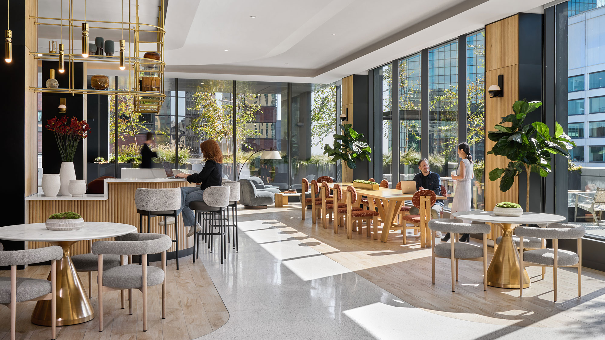 A group of people sitting at tables in a room with windows.