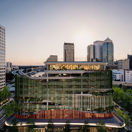 A large glass building with a city in the background.