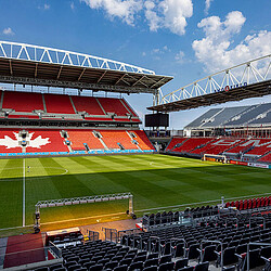 A sports stadium with a green field.