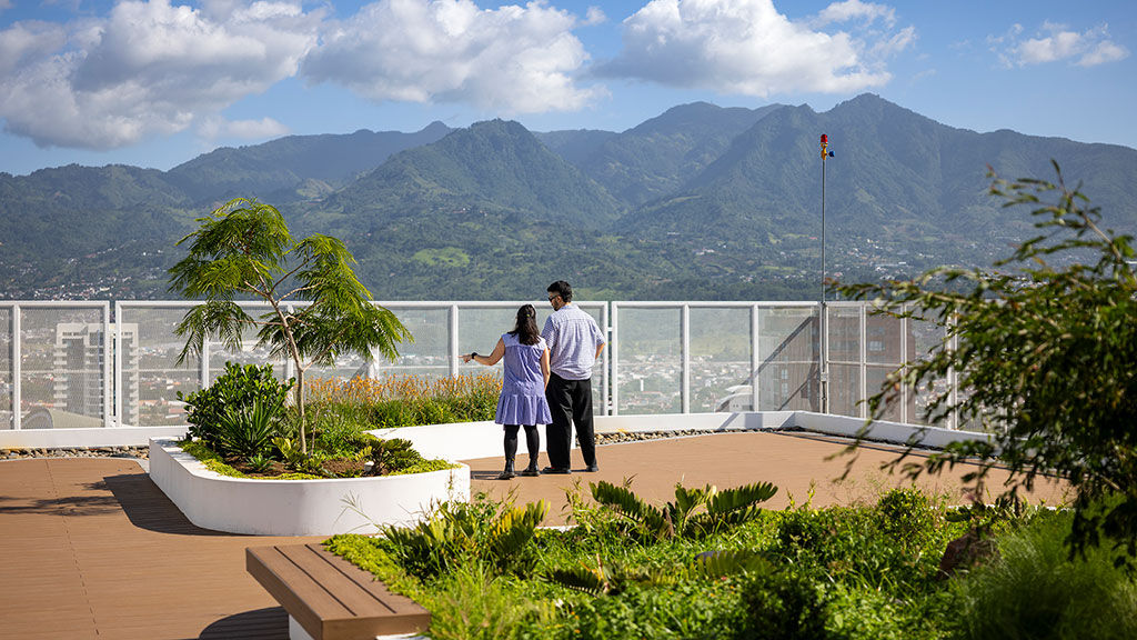 A man and woman standing on a balcony overlooking a body of water.