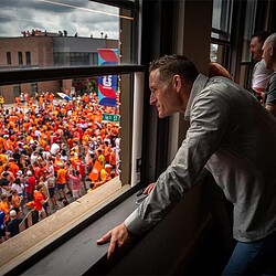 A man standing in front of a window with a crowd of people.