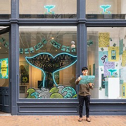 A person standing in front of a building with a mural on it.