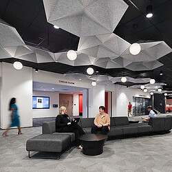 A group of people sitting on a couch in a room with a large ceiling and a large project.