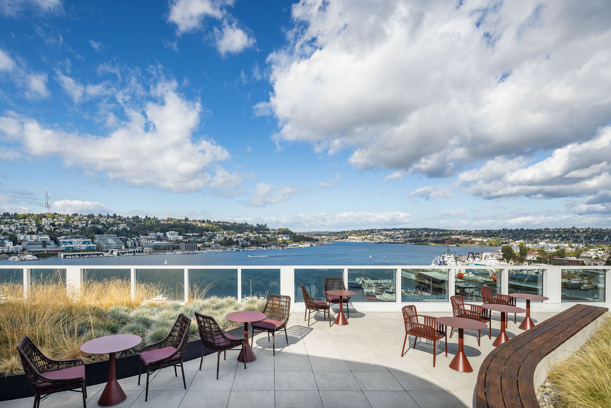 A patio with tables and chairs and a body of water in the background.