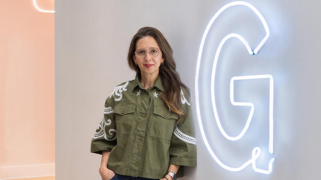 A woman standing in front of a wall with a logo.