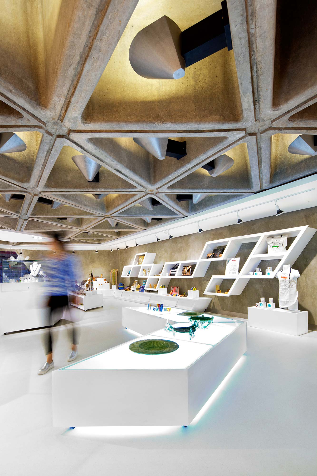 A room with a large ceiling and a large white table with a green bowl on it.