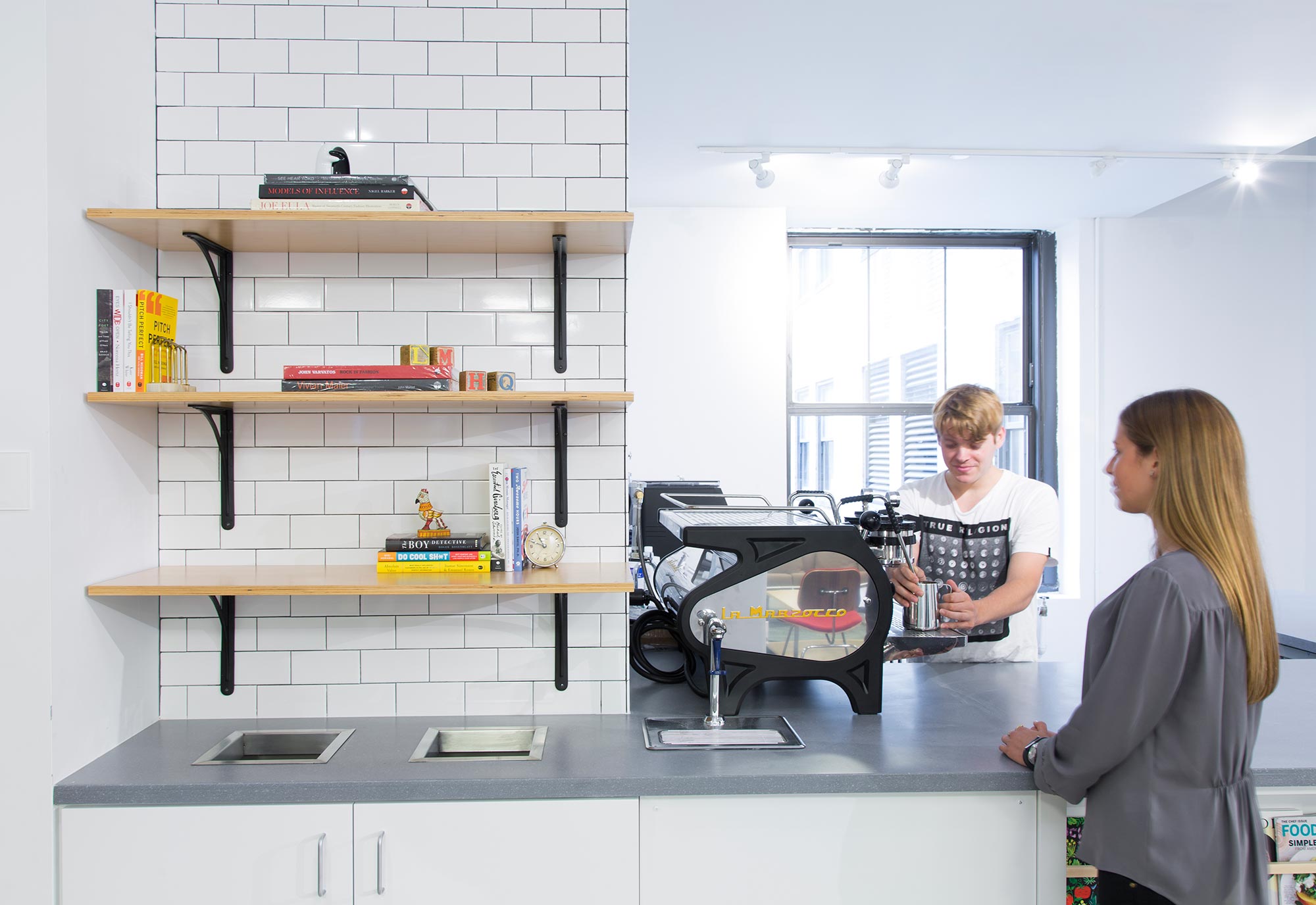 A man and a woman in a room with shelves and a table.