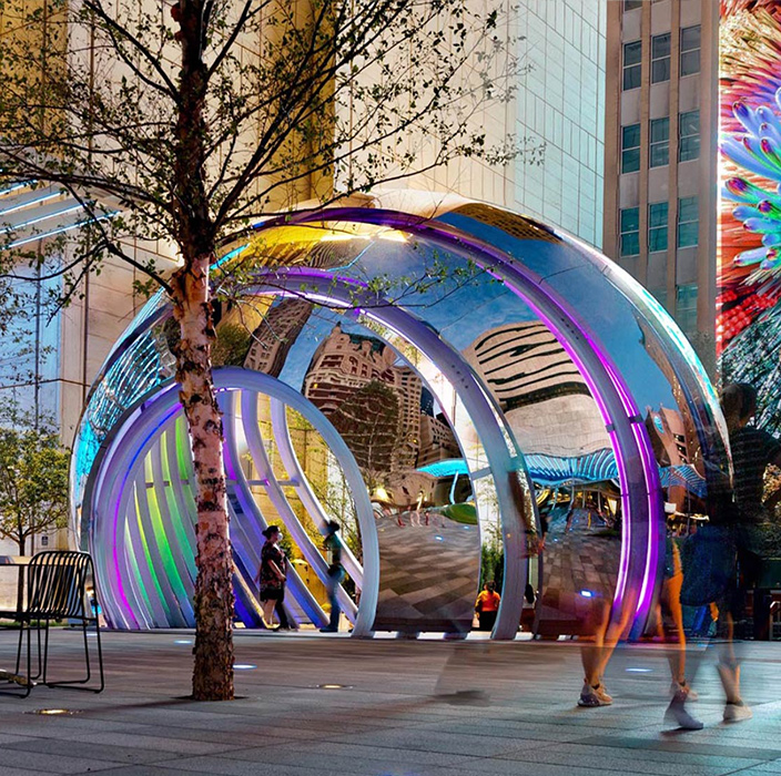 A group of people walking around a large sculpture.