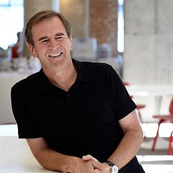 A man smiling with his arms crossed.