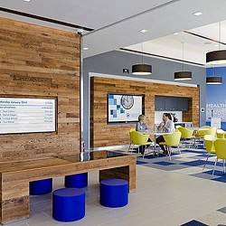 A couple of people sitting at a table in a room with a wood wall and a wood floor.