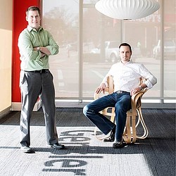 A person sitting on a stool next to a person standing.
