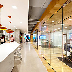 A long hallway with people sitting at tables and a glass wall.