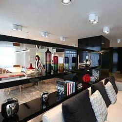 A person standing in a room with a counter and shelves with books.