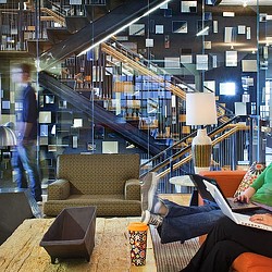 A person sitting on a couch with a laptop in a room with a staircase.