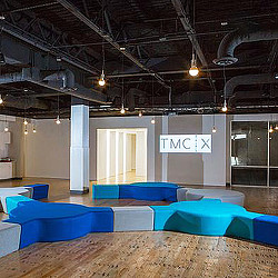 A room with blue couches and a sign on the ceiling.
