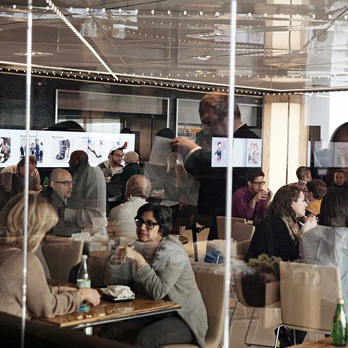 A person standing in front of a mirror in a room with other people.