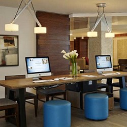 A desk with a computer and a vase of flowers.