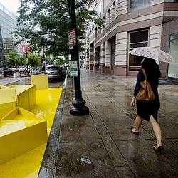 A person walking down a sidewalk with an umbrella.