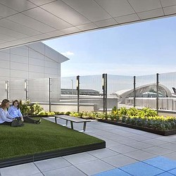 A couple of women sitting on a bench in a large room with a glass wall and a large.