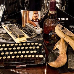 A bottle of beer next to a typewriter and a bottle of beer.