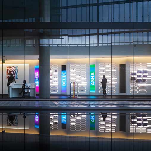 A large glass building with a few people walking around.