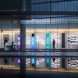 A large glass building with a few people walking around.