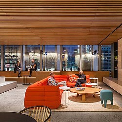 A group of people sitting on a couch in a room with windows.