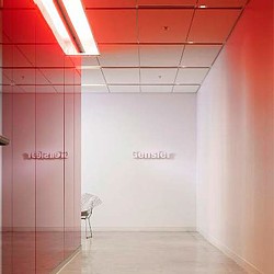 A room with a chair and a white wall with a red light.