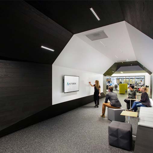 A person standing in a room with people sitting at desks.