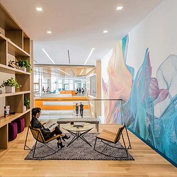 A person sitting in a chair in a room with a large painting.