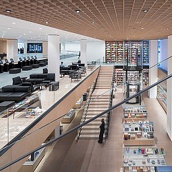 A person walking in a large room with rows of chairs and tables.