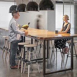 A man and woman sitting at a table with a woman standing behind them.