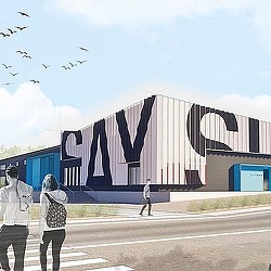 A group of people walking in front of a building with a large flag.