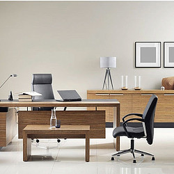A desk with a laptop and a chair in a room with a white wall.
