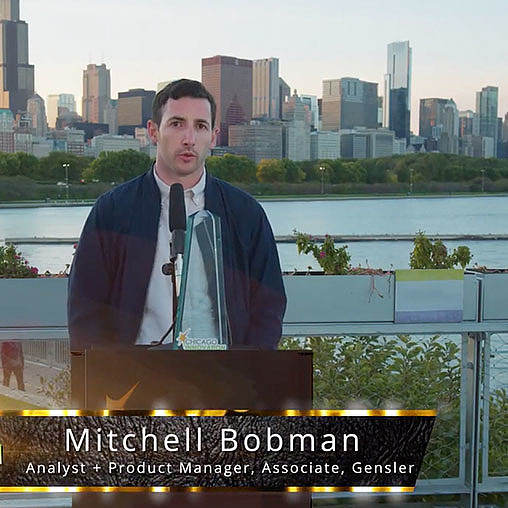 A man standing at a podium with a microphone in front of a city.