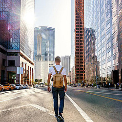 A person standing in the middle of a street with tall buildings.