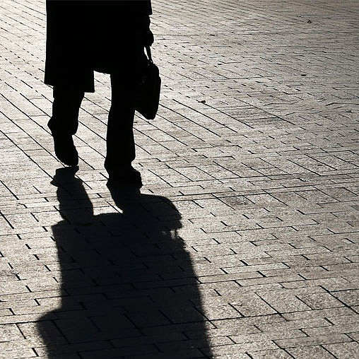 A couple of people walking on a brick road.