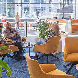 A group of people sitting at a table in a room with windows.