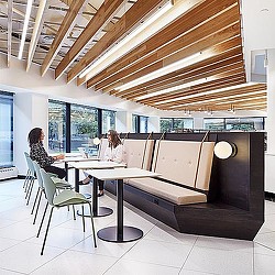 A couple of women sitting at a table in a room with windows.