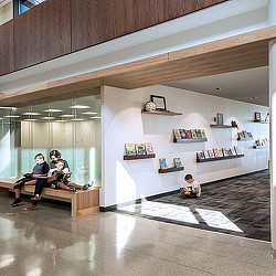 A couple of people sitting on a bench in a room with shelves.