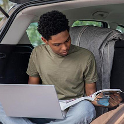 A man reading a book in a car.