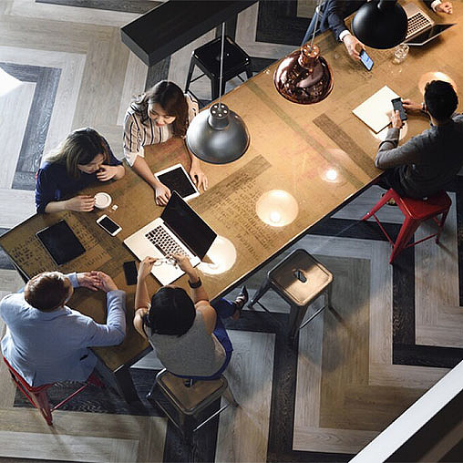 A group of people sitting around a table with laptops.