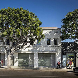 A white building with a tree in front of it.