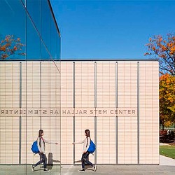 A couple of women walking by a large white building.