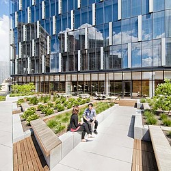 A man and woman sitting on a bench outside of a building.